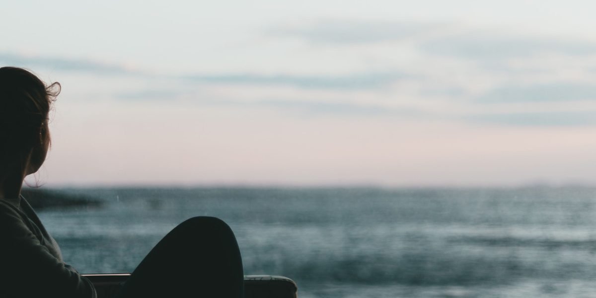 A person stands on a balcony overlooking the ocean, embodying the serene and private coastal luxury of Monterey.